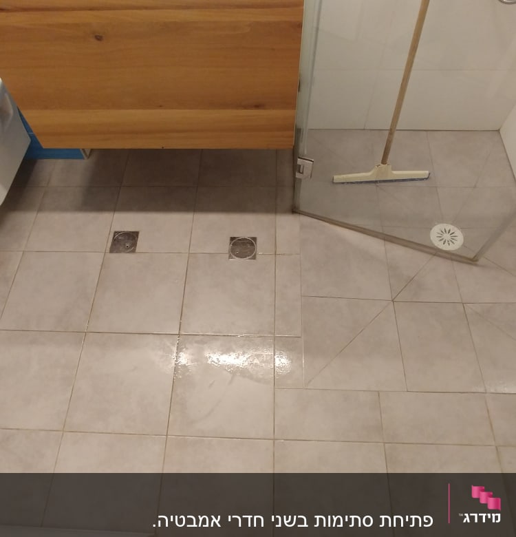 רצפת חדר אמבטיה עם פתחי ניקוז ומגב